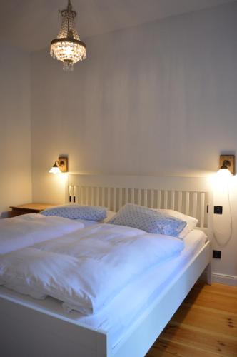 a bedroom with a large white bed and a chandelier at Burger Fährhaus in Burgerfeld