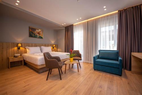 Habitación de hotel con cama y silla azul en Azure Inn Hotel, en Sarandë