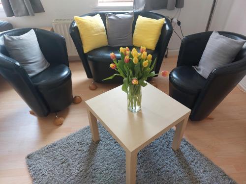 a vase of flowers on a coffee table in a living room at Schöne Zwei-Zimmer-Wohnung "W2" mit 4 Einzelbetten und WLAN in Zwenkau bei Leipzig im Neuseenland in Zwenkau