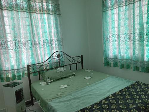a bed in a bedroom with blue curtains at Narayana Illam in Nilai