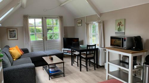 uma sala de estar com um sofá e uma televisão em Rob's Cottage em Schoorl