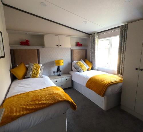 a bedroom with two beds with yellow sheets and a window at Macaw Lodge in Malton