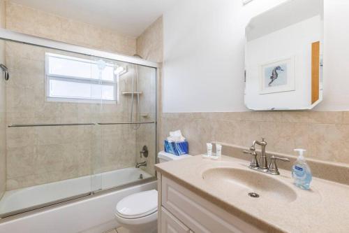 a bathroom with a sink and a toilet and a window at West Boca Seashell House in Boca Raton