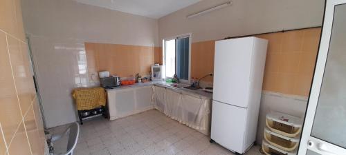 a kitchen with a white refrigerator and a window at Sahline, entre Sousse et Monastir, 2 Km de la plage in Sahline