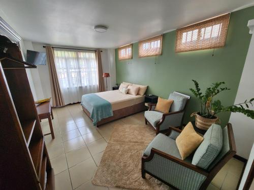 a bedroom with a bed and a couch and chairs at Queen Maxima by Prins Hendrik Suites in Paramaribo