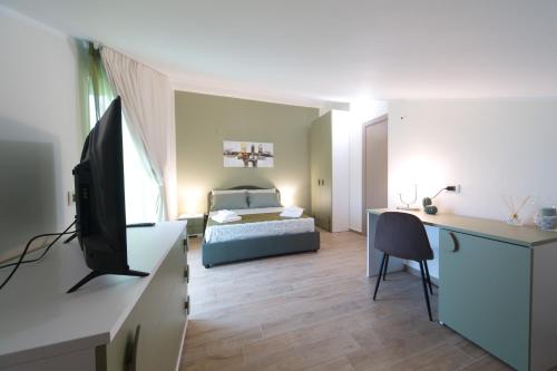 Habitación con cama y escritorio con TV. en Slow Chic Apartment BeB Policlinico en Messina