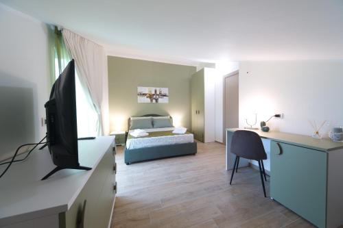a bedroom with a bed and a desk with a television at Slow Chic Apartment BeB Policlinico in Messina