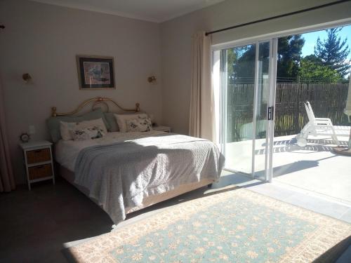 a bedroom with a bed and a sliding glass door at Farm House Plettneberg Bay in Plettenberg Bay