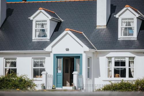 a white house with a blue door and a black roof at Móinéir House in Kilkee