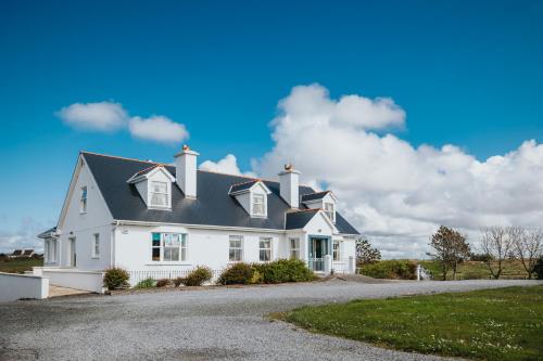 una casa blanca con techo negro en Móinéir House, en Kilkee