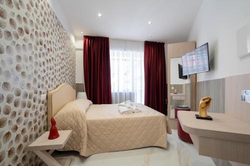 sypialnia z łóżkiem i telewizorem na ścianie w obiekcie P.C. Boutique H. Vesuvius, Napoli Centro, by ClaPa Group w mieście Napoli