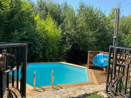 a swimming pool with a wooden deck and a blue swimming poolvisor at Maison Gecko in Ornaisons