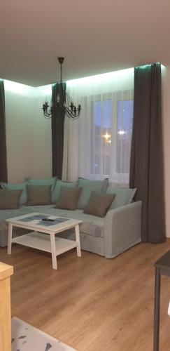 a living room with a white couch and a table at Apartamentai centre in Klaipėda