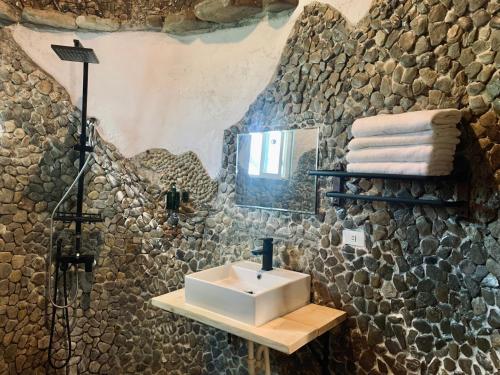 baño con lavabo y pared de piedra en 滿丘石頭屋ManChill en Manzhou