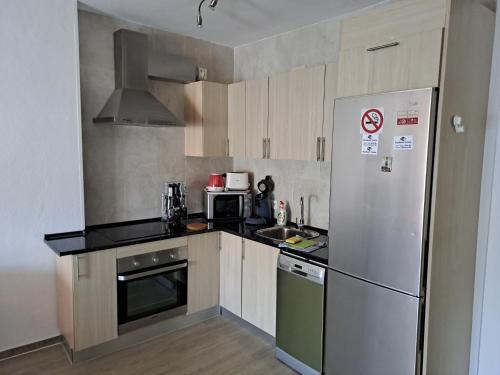a small kitchen with a refrigerator and a sink at BenalBeach Yasmine in Benalmádena