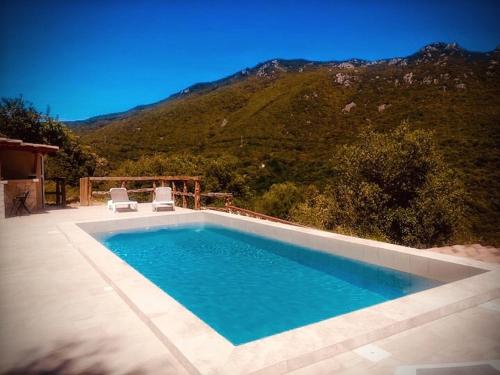a swimming pool with two chairs and a mountain at Casa Stella in Olmeto