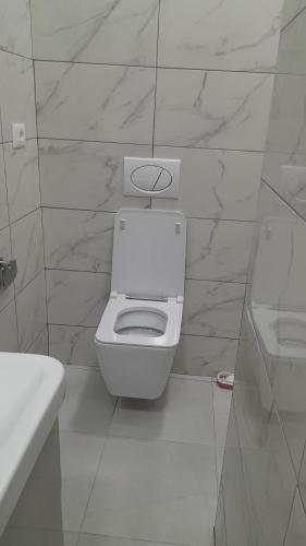 a white bathroom with a toilet and a sink at Luxury Dennis Home in Sarandë