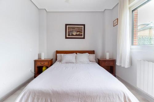 1 cama blanca en un dormitorio blanco con 2 mesitas de noche en La Solana de Boo en Boó de Piélagos
