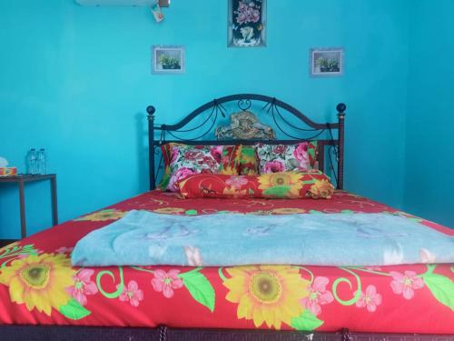 a bed with a red bedspread with flowers on it at Cowang Dereng Home Stay in Labuan Bajo