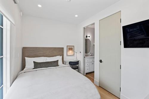 a white bedroom with a white bed and a television at Casa Jardin - Boutique Suites in Downtown Santa Barbara in Santa Barbara