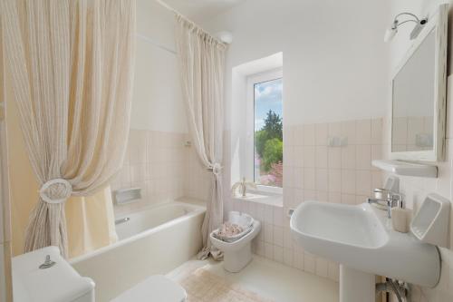 La salle de bains blanche est pourvue d'une baignoire, d'un lavabo et de toilettes. dans l'établissement Triklino Estate, à Áfra
