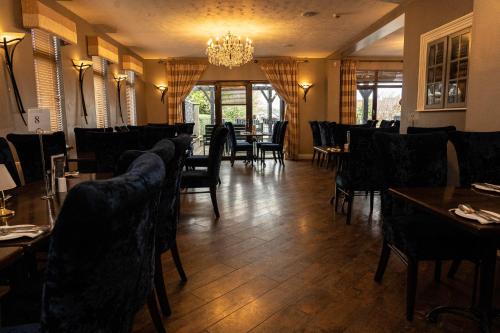 uma sala de jantar com cadeiras e mesas e um lustre em Golf Links House em Newcastle