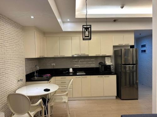 a kitchen with white cabinets and a stainless steel refrigerator at The Pearl - Venice Luxury Residences McKinley in Manila