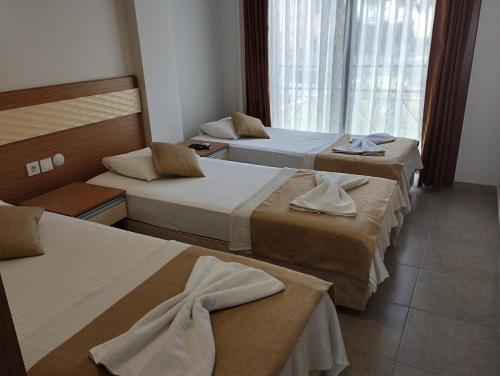 a hotel room with three beds and a window at Soleil Hotel in Kuşadası