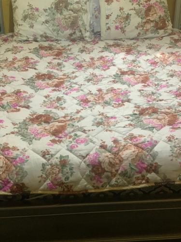 a bed with a floral comforter on it at Dar Dyafa 