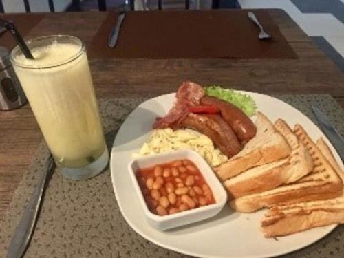 a plate of breakfast food with eggs bacon beans and a glass of milk at El-King Home Lodge in Afwerasi