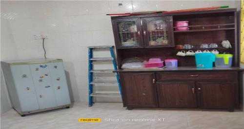 a kitchen with a refrigerator and a wooden cabinet at Homestay Tengku Maheran in Jitra