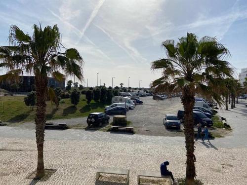 a group of cars parked in a parking lot with palm trees at Atlantic Lodge, 1ª linha de praia! in Costa da Caparica