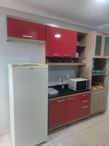 a kitchen with red cabinets and a microwave at AP inteiro+menor preço+ar condicionado in Goiânia
