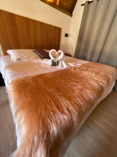 a bed with an orange fur blanket on it at VILLA ITÁLIA CHALÉ in Santo Antônio do Pinhal