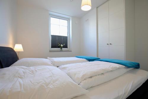 a bedroom with two white beds and a window at Villa Petersen Ankerplatz 3 in Wangerooge