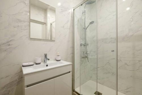 La salle de bains blanche est pourvue d'un lavabo et d'une douche. dans l'établissement Villa Forestière Studio Le Châtaignier, à Quincy-Voisins