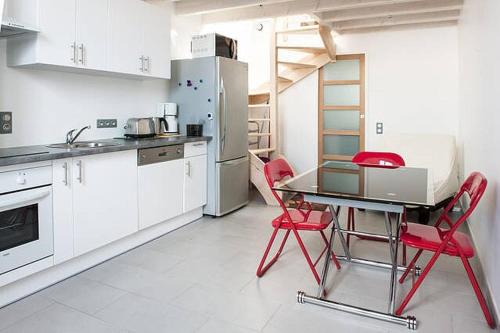 La cuisine est équipée de chaises rouges, d'une table et d'un réfrigérateur. dans l'établissement Superbe T1 bis de 35 m2 - stationnement gratuit - proche gare et port - Apt Droit, à La Rochelle