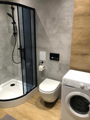 uma casa de banho com um WC, um chuveiro e uma máquina de lavar roupa em Apartament BROWARNY em Ostrów Wielkopolski