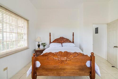 1 dormitorio con cama de madera en una habitación blanca en Rose View Apartment en Montego Bay