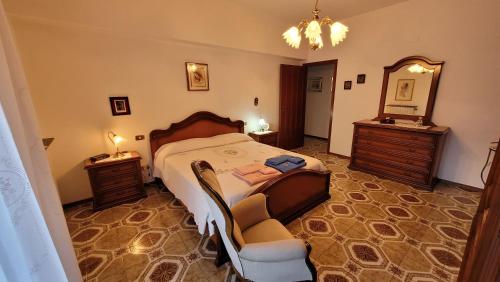 a bedroom with a bed and a chair and a mirror at La casa di nonna Carmelina in Milazzo
