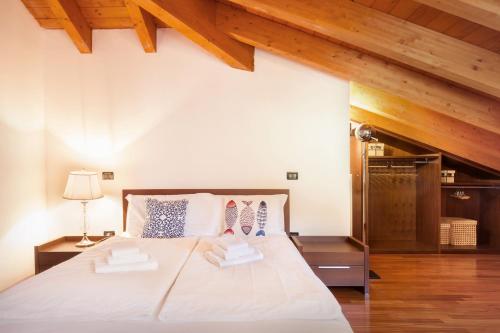 - une chambre avec un grand lit blanc et des plafonds en bois dans l'établissement La Fortezza Apartment, à Peschiera del Garda