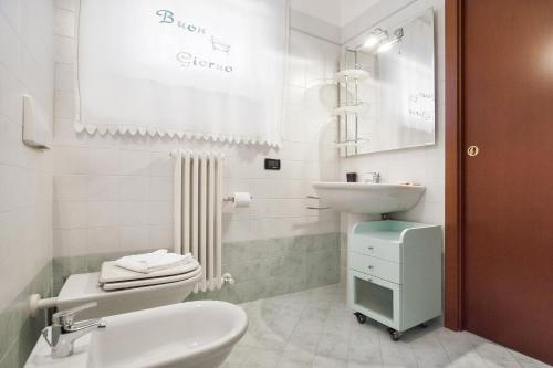 La salle de bains blanche est pourvue d'un lavabo et de toilettes. dans l'établissement La Fortezza Apartment, à Peschiera del Garda