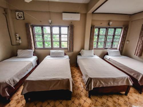 a room with three beds in it with windows at Sabaydee Guesthouse in Ban Houayxay