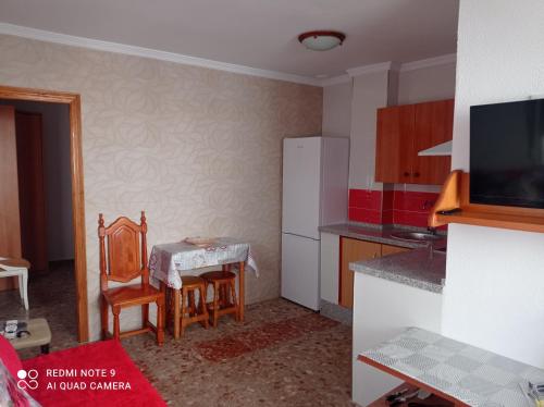 Il comprend une petite cuisine avec une table et un réfrigérateur blanc. dans l'établissement habitación turquesa, à Barbate