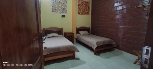 a room with two beds and a brick wall at Suites Hostal V&D Caranavi, La Paz in Caranavi