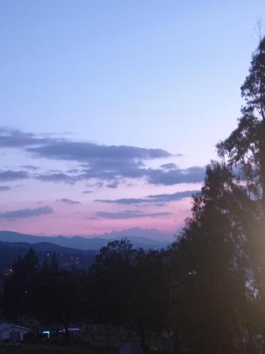 a view of a sunset with trees and mountains at Hospedaje Guatavita cabaña tippie in Guatavita