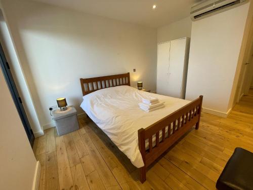 um quarto com uma cama com lençóis brancos e pisos em madeira em Penthouse in Battersea amazing views of London em Londres