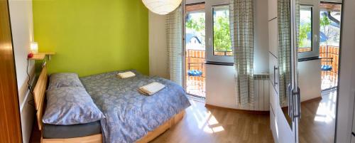 a bedroom with a bed and green walls and windows at Holiday Home Kristi in Bovec