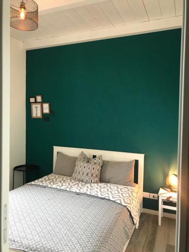 a bed in a room with a green wall at Mazzini apartment in Arona