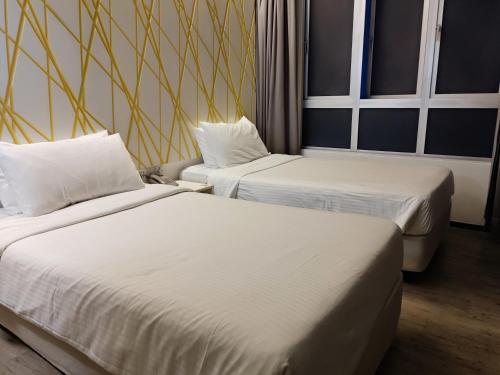 duas camas num quarto de hotel com lençóis brancos em Comfy Room In Genting Highlands em Genting Highlands